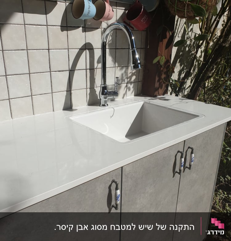 שיש לבן עם כיור וברז במטבח חיצוני